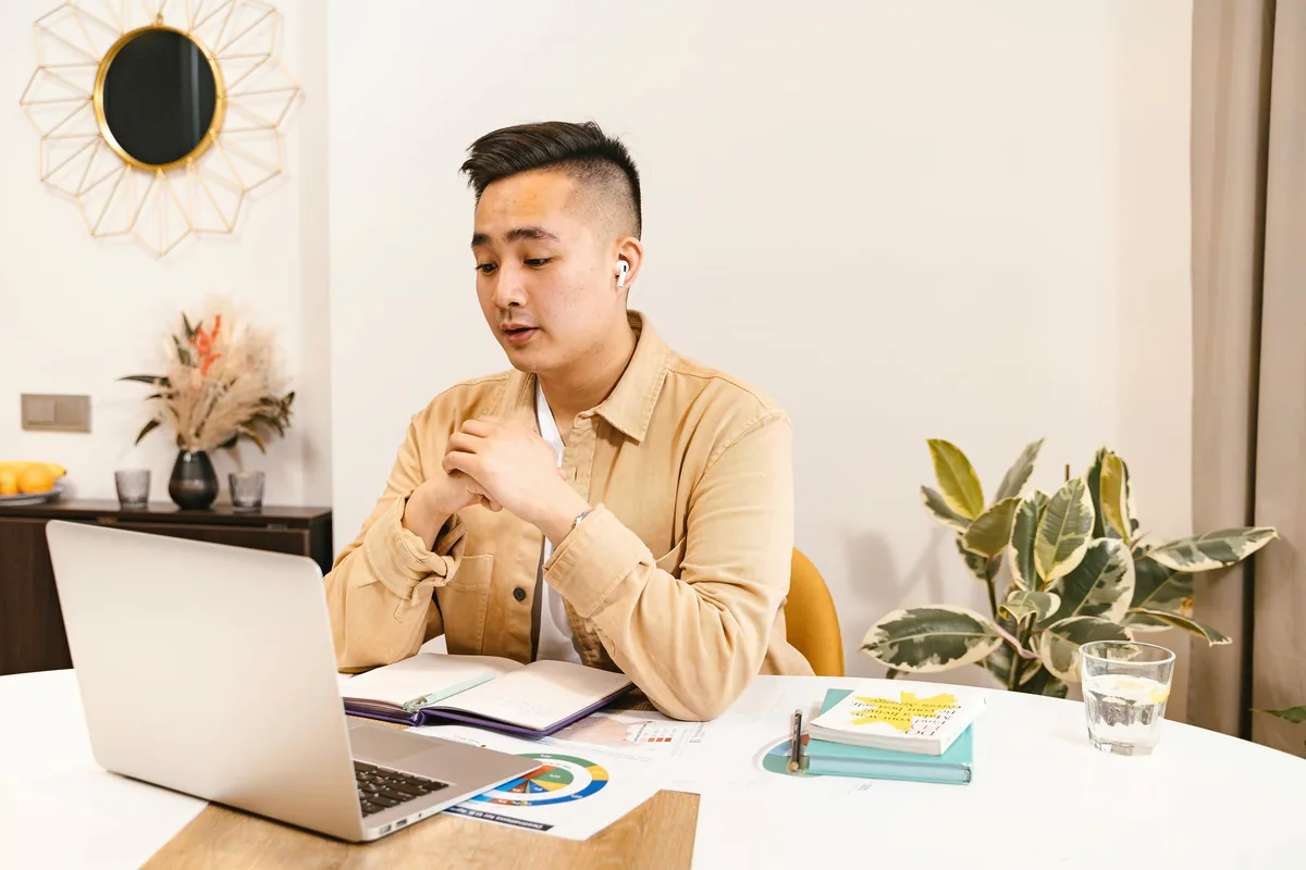 A practitioner in a video session, wearing an earbud and speaking warmly